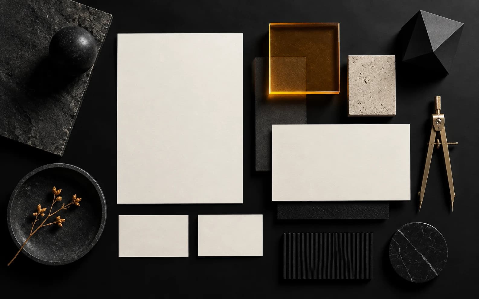 Black branding table with blank cards, geometric forms, and an amber material sample